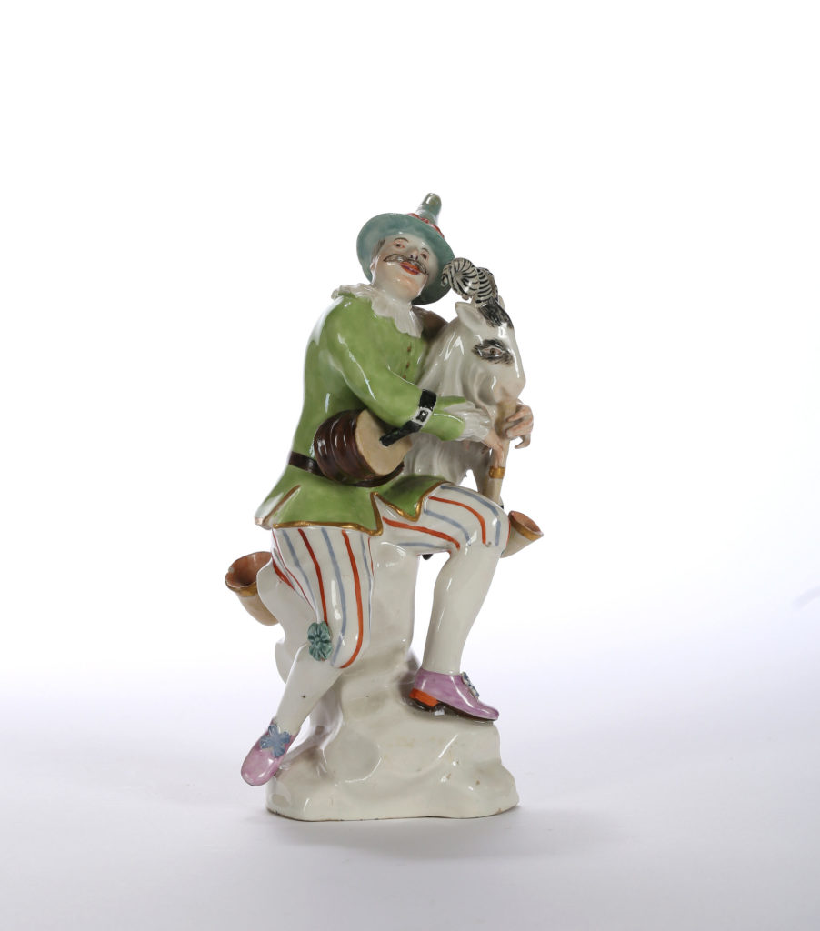 A HÖCHST FIGURE OF HARLEQUIN OR HANSWURST WITH BAGPIPE